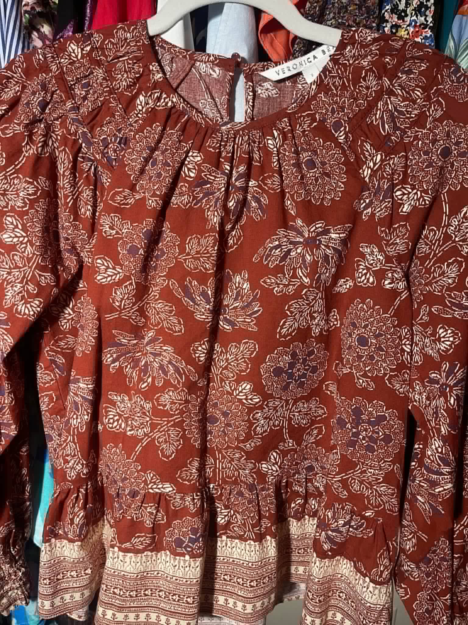 Veronica Beard floral blouse hanging on a rack.